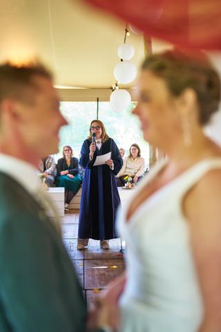 Ceremoniemeesteres spreekt gasten toe tijdens de bruiloft van Karlijn en Glenn bij Breezze in Vierpolders - Trouwshoot Stefan