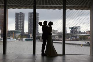 Bruidspaar silhouet voor panoramische ramen met uitzicht op Maas en Rotterdam skyline - Trouwshoot Stefan Segers