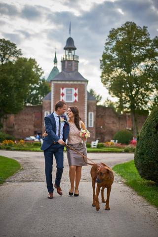Bruidspaar loopt hand in hand met hond langs historisch kasteel, destination wedding fotografie — Trouwshoot Stefan Sege