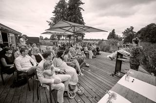 Bruidspaar Milou en Theron ceremonie op houten terras met gasten onder parasols - Trouwshoot Stefan Segers