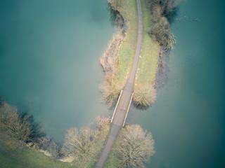 Jeroen en Martijn rijden over een smalle dijk tussen turquoise water en kale bomen - een moment van rust tijdens hun bruiloft