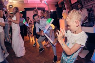 Bruidspaar Dennis en Kim danst feestelijk met gasten op trouwfeest, kinderen zwaaien met gekleurde staven, trouwreportage Kas