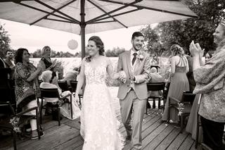 Bruidspaar Milou en Theron loopt lachend onder parasol bij receptie Kamerik Woerden, trouwreportage - Trouwshoot Stefan Seger
