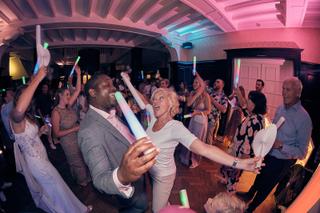 Bruidspaar Dennis en Jayce danst uitgelaten met gasten op trouwfeest, neon glow sticks, feestelijke trouwreportage Kasteel De