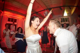 Bruidspaar Sanne en Ferry dansen feestelijk op trouwreportage, rode discosfeer met gasten - Trouwshoot Stefan Segers