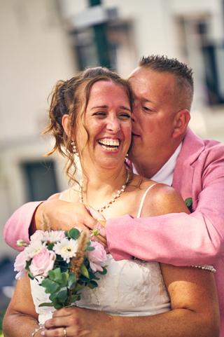 Diliana en Olav stralen van geluk op hun trouwdag in IJsselstein. Bruidegom knuffelt zijn bruid van achteren terwijl zij lach