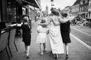 Bruid Ellen en bruidsmeisjes lopen hand in hand door historische straat Vianen, romantische trouwreportage - Trouwshoot Stefa