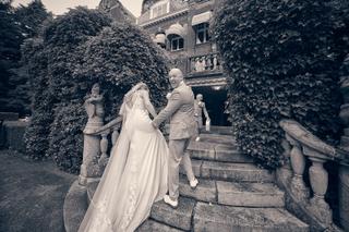 Bruidspaar Dennis en Kim lacht op traptreden bij Kasteel De Hooge Vuursche, ivygeraniums framing, romantische trouwreportage