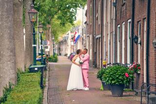 Diliana en Olav kussen in een charmante straatje van IJsselstein, omgeven door bakstenen huizen en bloeiende plantenbakken -