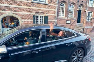 Bruidspaar Diliana en Olav zwaaien naar gasten vanuit de auto na hun trouwerij in IJsselstein - Trouwshoot Stefan Segers