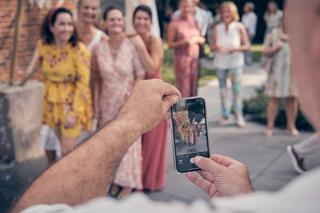 Gast fotografeert bruidspaar Elles en Bram met smartphone tijdens ceremonie op Het Dikke Torentje in Eemnes - Trouwshoot Stef