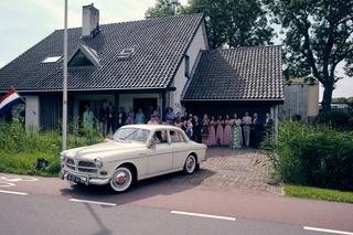 Julia en Rens verlaten in stijl 't Wapen van Zoetermeer in een klassieke Volvo, omringd door trouwinvitees - Trouwshoot Stefa