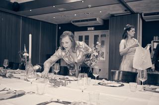 Moeder van de bruid arrangert bloemen aan tafel tijdens het huwelijksfeest van Julia en Rens - Trouwshoot Stefan Segers