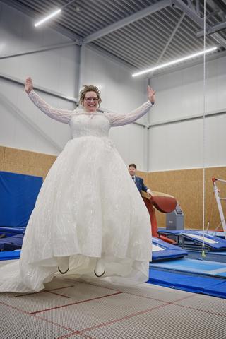 Bruid Christa springt juichend op trampolines in Gymworld Zoetermeer, vrolijke trouwreportage - Trouwshoot Stefan Segers