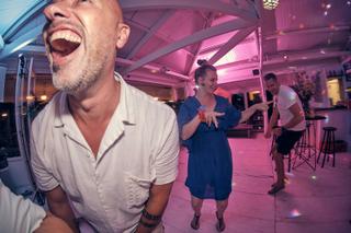 Bruidsgasten dansen uitgelaten in roze verlichting op Strandclub Naturel, festief trouwfeest - Trouwshoot Stefan Segers