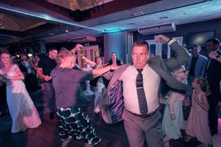 Bruidegom Herre danst uitgelaten met gasten op trouwfeest, feestelijke sfeer in zaal 't Wapen van Zoetermeer, trouwreportage