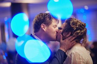 Bruidspaar Christa en Gerco zoenen onder blauwe sfeerverlichting op trouwfeest Wapen van Zoetermeer - Trouwshoot Stefan Seger