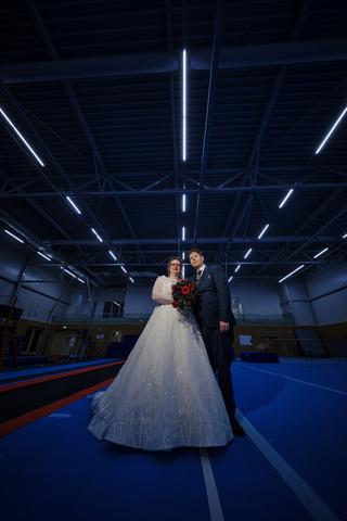 Bruidspaar Christa en Gerco poseert in moderne sporthal Gymworld Zoetermeer, trouwreportage met rode en blauwe matten - Trouw
