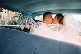 Bruidspaar Lotte en Daniel kussen in vintage auto met bruidsbloemen - Trouwshoot Stefan Segers