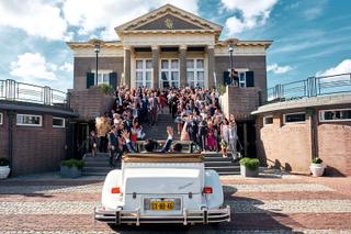 Bruidspaar Janet en Yu verlaten stadhuis Zoetermeer in vintage auto, trouwreportage met gasten op trap - Trouwshoot Stefan Se