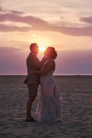 Bruidspaar Mirjam en Jorg omhelzen elkaar bij zonsondergang op het strand, romantische trouwreportage Ouddorp - Trouwshoot St