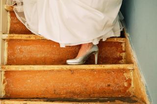 Bruid Kimberly in witte jurk en zilveren schoenen op houten trap stadhuis Noordwijkerhoute - Trouwshoot Stefan Segers