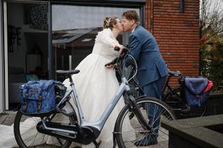 Bruidspaar Christa en Gerco kust op e-bike bij Stadhuis Zoetermeer, trouwreportage bruidsfotografie - Trouwshoot Stefan Seger