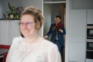 Bruidegom Gerco met rode bloemen kijkt naar bruid Christa in moderne keuken, trouwreportage Zoetermeer - Trouwshoot Stefan Se
