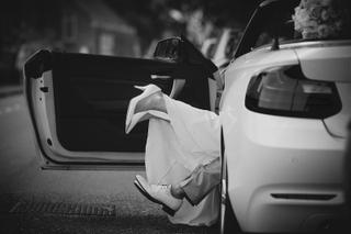 Bruid Jooske stapt elegant uit de auto, haar witte jurk zwiepend in beweging - Trouwshoot Stefan Segers