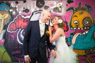 Bruidspaar Mathijs en Marijn lacht voor felgekleurde graffiti-muur, trouwreportage Hoeve Kromwijk Zoetermeer - Trouwshoot Ste