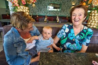 Daphne en Edwin vieren hun bruiloft op Hoeve Kromwijk met familie. Grootmoeder straalt van blijdschap met het kleine meisje t