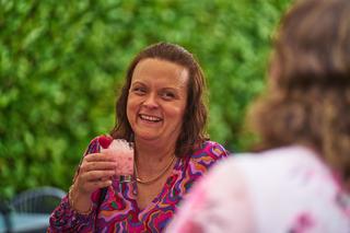 Daphne lacht voluit met een roze drankje in de hand, genietend op Hoeve Kromwijk Zoetermeer - Trouwshoot Stefan Segers